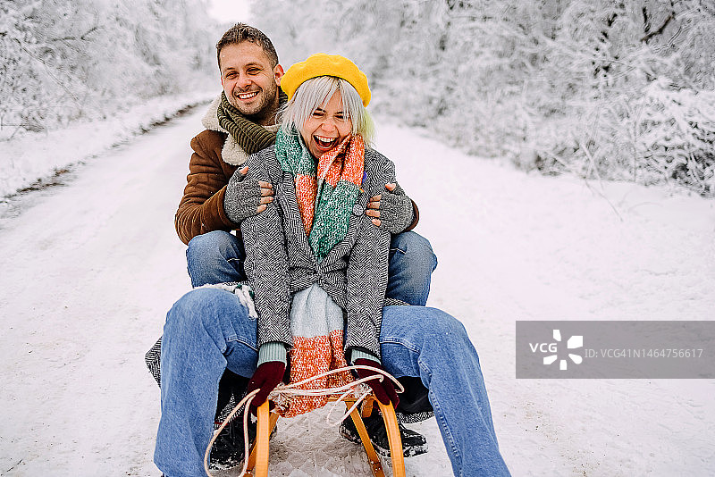 一对夫妇坐在雪橇上滑下山图片素材