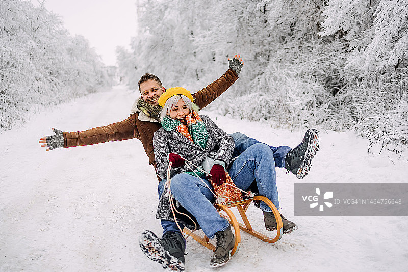 一对夫妇坐在雪橇上滑下山图片素材