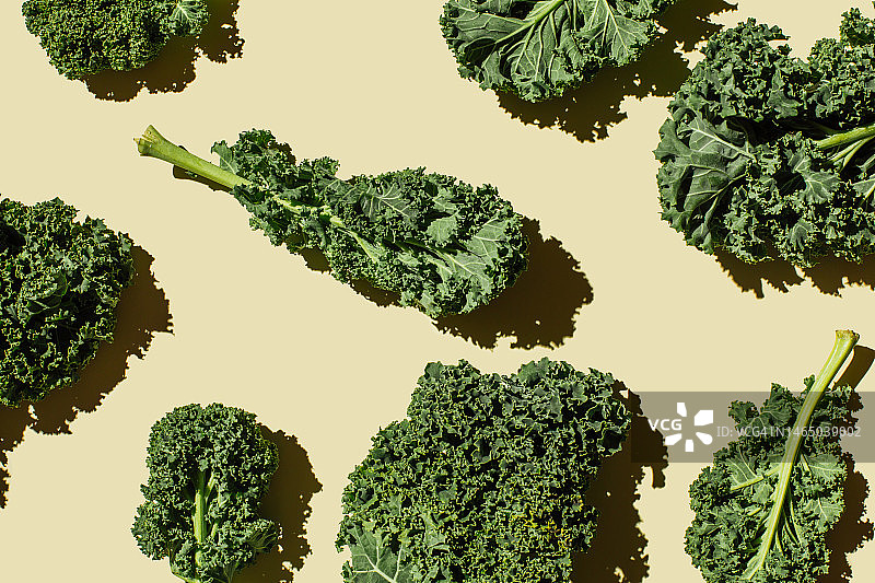 在米色背景上的新鲜绿色有机羽衣甘蓝叶子图案。健康食品、饮食与排毒概念。平铺，俯视图图片素材