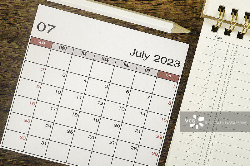 2023年日历台:七月是组织者在木制背景下用白色铅笔和检查表纸来计划和截止日期的月份。图片素材