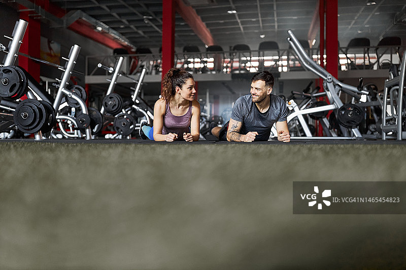快乐的运动员夫妇在健身房休息时聊天。图片素材