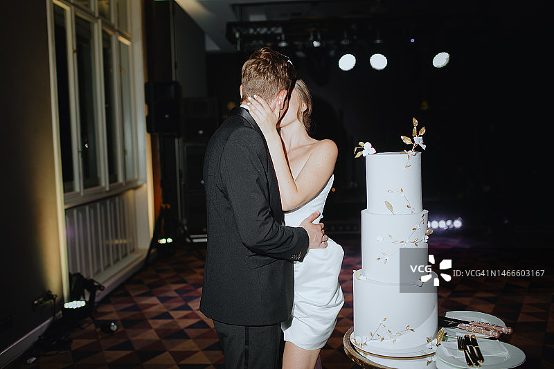 新婚夫妇在婚礼蛋糕旁接吻图片素材
