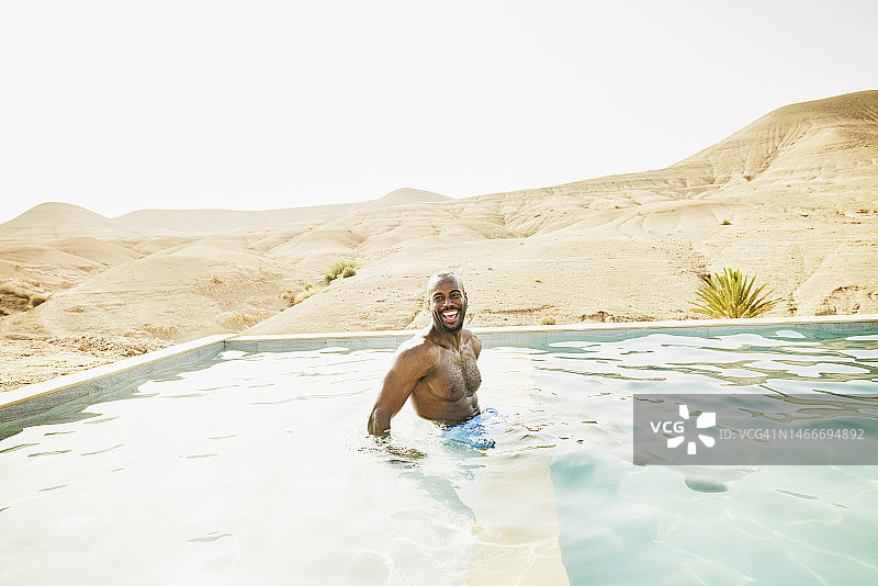 宽阔的镜头，笑的人放松在游泳池在摩洛哥沙漠营地图片素材