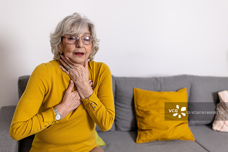 一位患有慢性疾病的老年妇女感到喉咙难以忍受的疼痛。图片素材