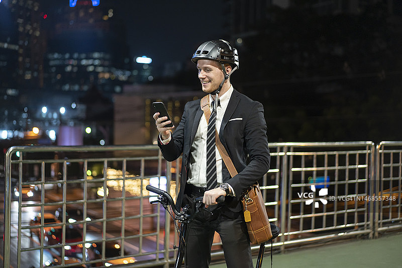 年轻的商人推着自行车，拿着智能手机图片素材