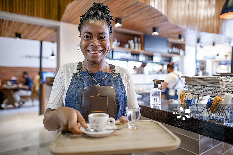 微笑的非洲女服务员在咖啡店为顾客服务图片素材