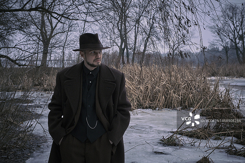 侦探男子穿着复古软呢帽，走在冬季公园位置图片素材