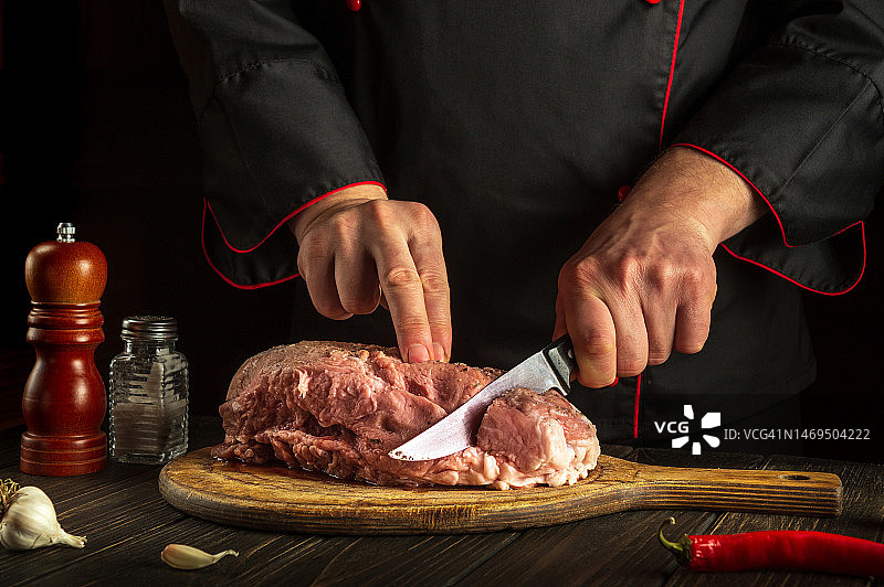 专业厨师在烤之前先用刀切肉。餐厅餐桌上为准备美味午餐或晚餐而放的香料图片素材