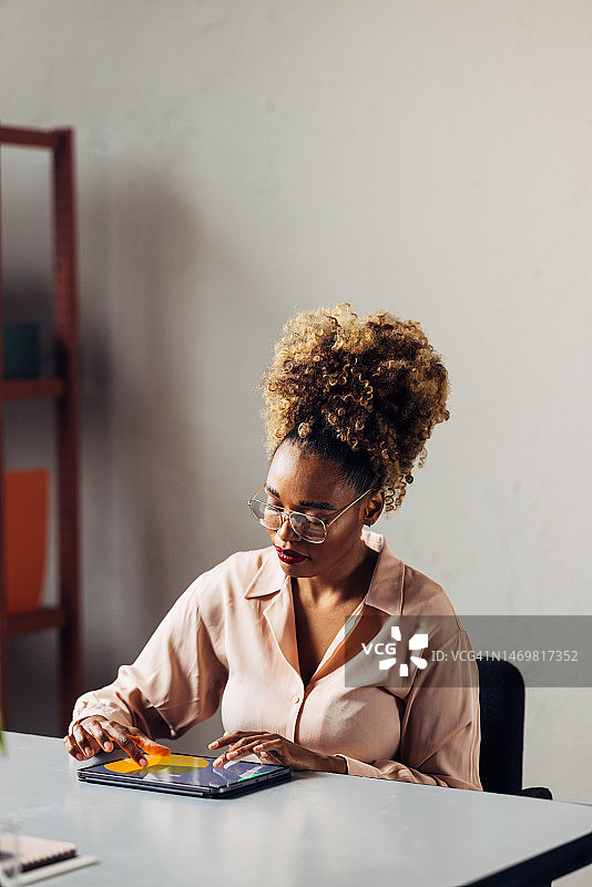 一个有着金色卷发的严肃美丽的女商人一边工作一边看着平板电脑图片素材