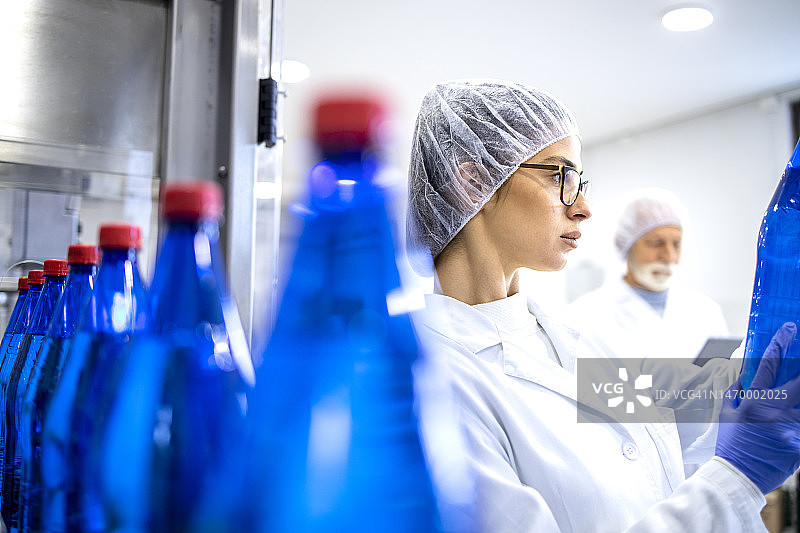 装瓶厂工人检查产品质量和生产率。图片素材