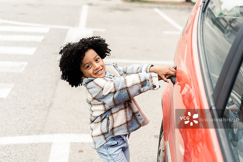一个可爱的小非裔美国男孩打开车门的肖像图片素材