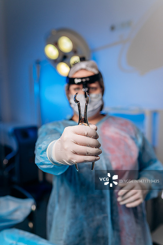 一名女外科医生在手术室里拿着肛门扩张器。一位戴着医用口罩的医生正在准备结肠直肠外科手术的医疗器械图片素材