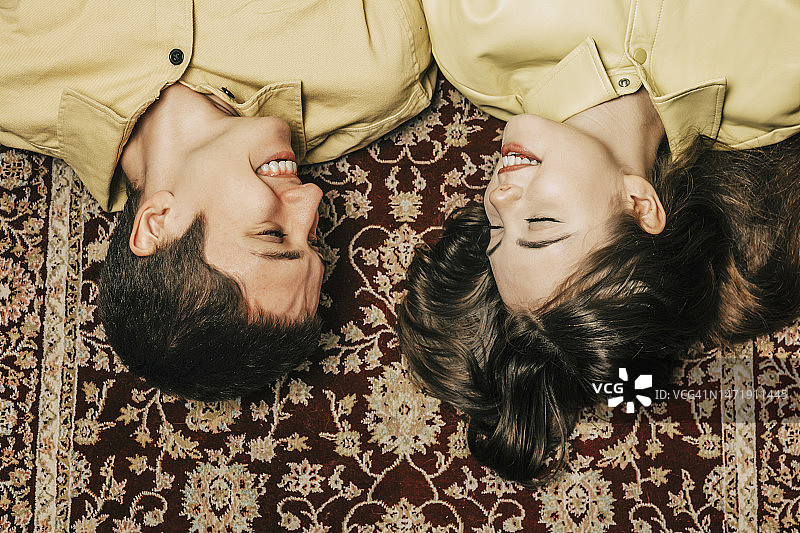幸福的小情侣躺在家里的地毯上图片素材