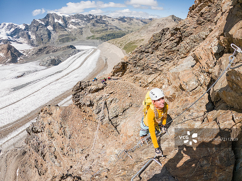 高角度的观点，妇女在Via Ferrata攀登，后面的冰川图片素材