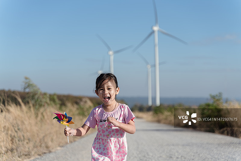 可爱的亚洲儿童女孩正在运行和玩风力发电机玩具与乐趣在风力发电机领域图片素材