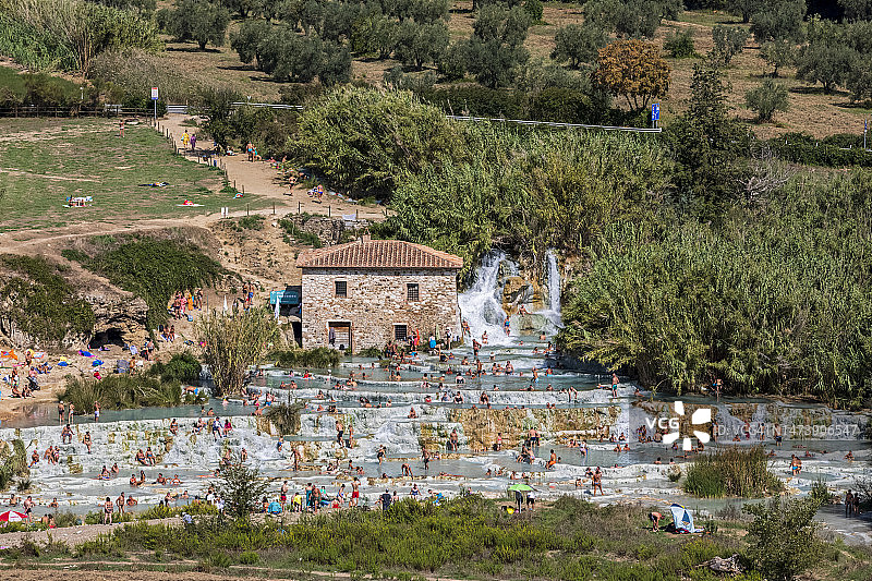 意大利，托斯卡纳，萨图尼亚，人们在卡斯卡特德尔穆里诺温泉池洗澡图片素材