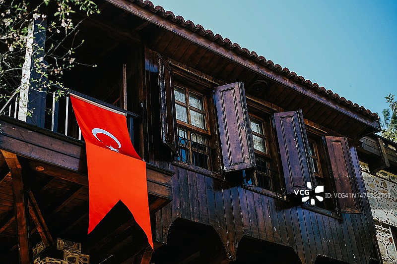 一面巨大的红色土耳其国旗在土耳其的一个旧工作的正面。土耳其度假。阿拉尼亚的老木屋。美丽的土耳其阿拉尼亚图片素材