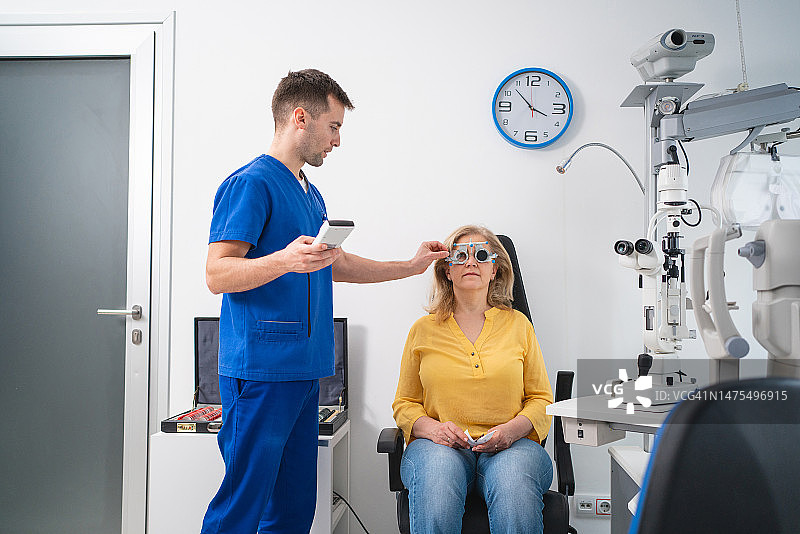 男眼科医生，检查老年女性患者视力，同时使用试用镜架和不同的镜片图片素材