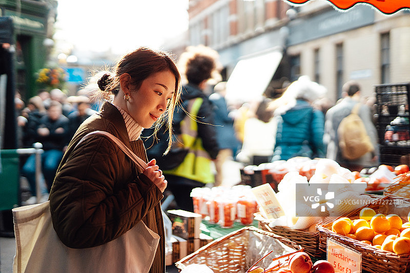 年轻的亚洲妇女在当地农贸市场购买水果和蔬菜图片素材