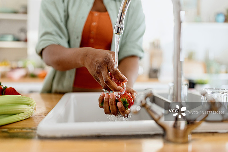 一个女人在厨房里洗草莓的特写图片素材