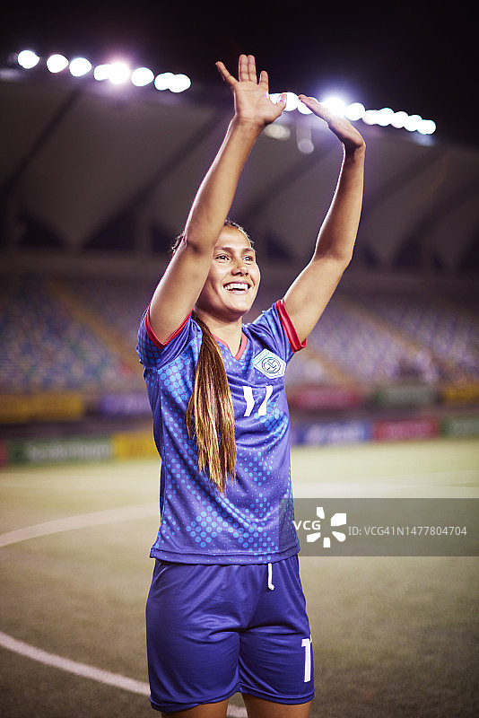 快乐的女子足球运动员向体育场的人群挥手图片素材