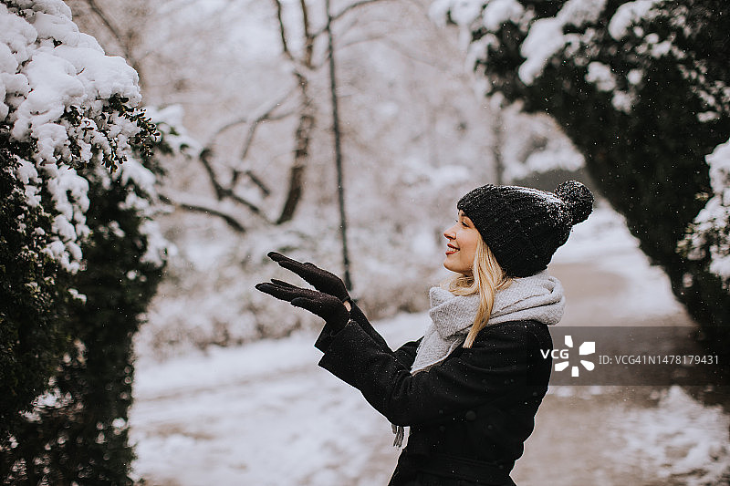年轻女子在雪中享受温暖的衣服图片素材