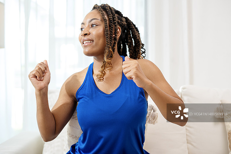 帮助情绪通过我们的身体与柔软的有氧舞蹈音乐在你的家。一名年轻的非裔美国女性在直播有氧运动课后移动身体。图片素材