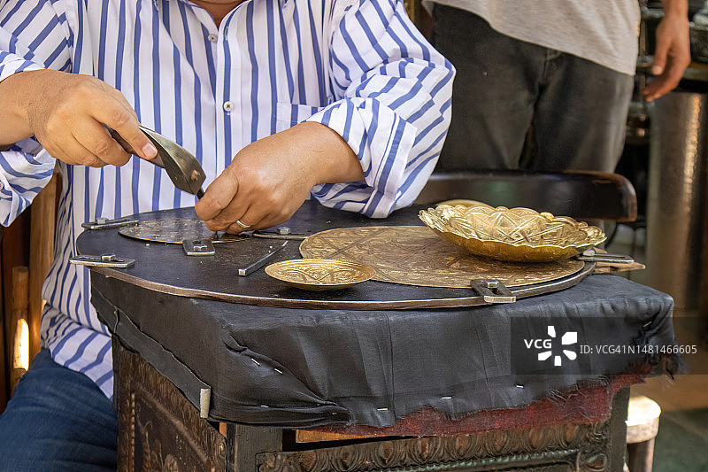 在Khan Al Kalili集市上，工匠雕刻铜板图片素材
