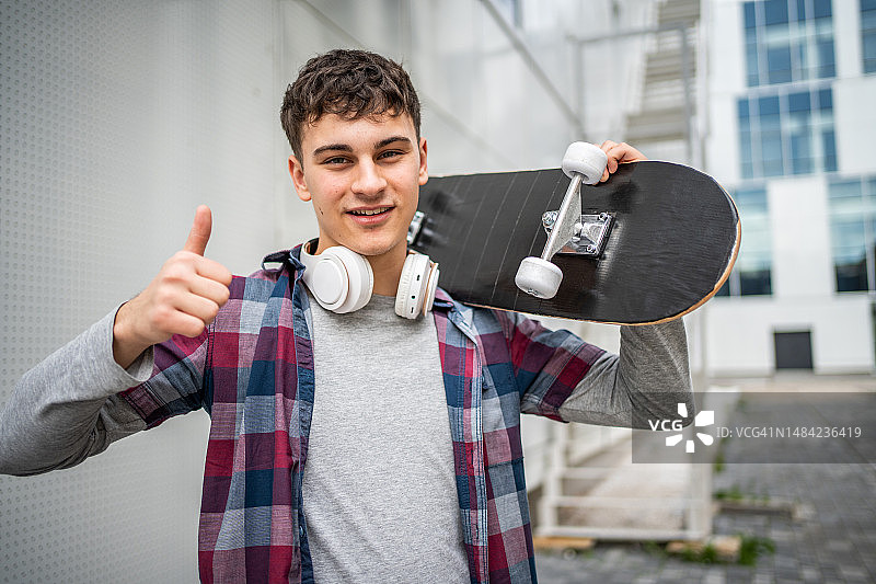 一个年轻人拿着滑板在外面的镜头图片素材
