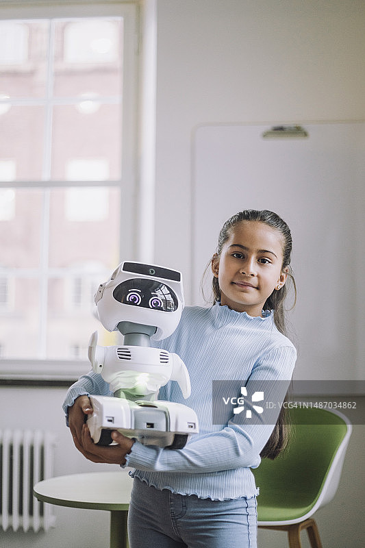 女孩抱着社交机器人站在创新实验室的肖像图片素材