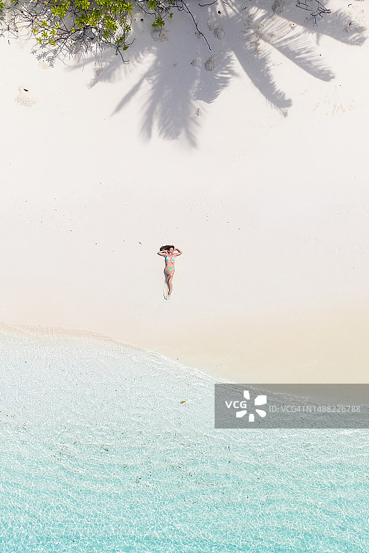 无人机拍摄的一名女子躺在沙滩上图片素材