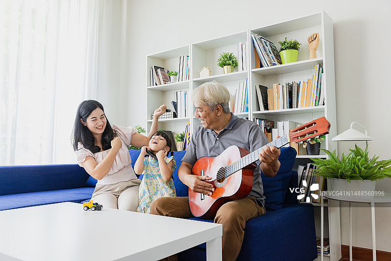 孙女和爷爷、妈妈在客厅里弹吉他。图片素材