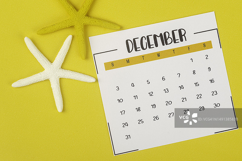2023年日历桌:12月是组织者计划和截止日期的月份，在黄色纸张背景上画一只海星。图片素材