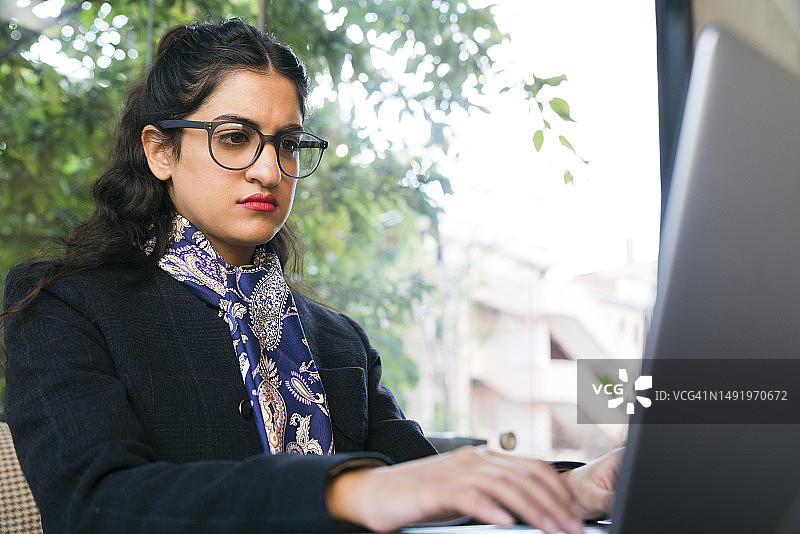 一个年轻女子被电脑显示屏包围着。一位女商人看着显示器上显示数据的移动图表，眼镜上的图像反射出来。图片素材