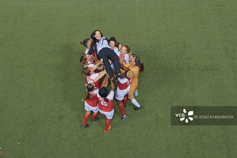 一支欣喜若狂的足球队将他们的教练举到空中庆祝图片素材