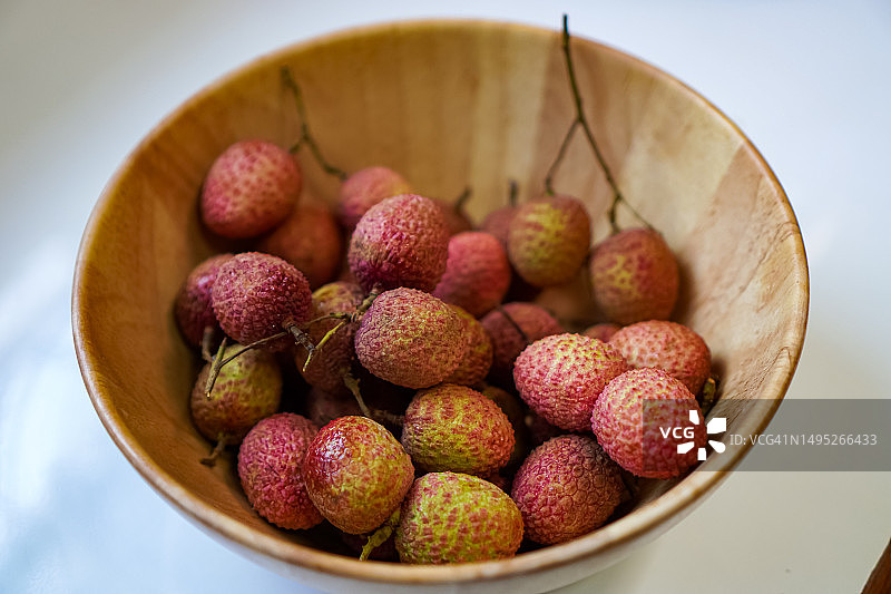 一张特写照片显示了一组荔枝水果排列在一个漂亮的即食木碗里。图片素材