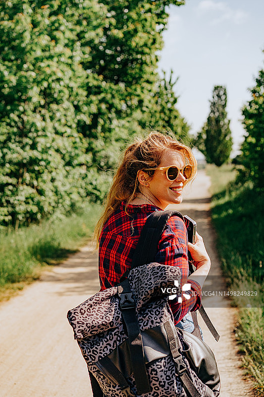 快乐的红发女人背着背包在夏天独自旅行图片素材