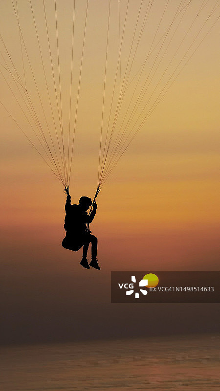 摩洛哥，日落时分，男子滑翔伞的剪影映衬着天空图片素材