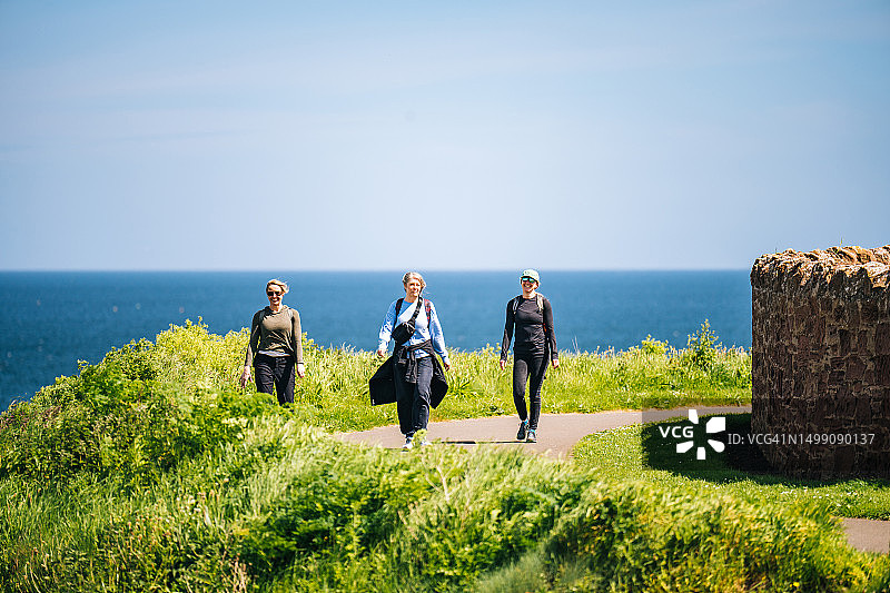朋友们沿着一个郁郁葱葱的海岬徒步旅行图片素材