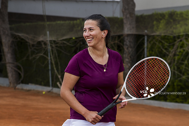 在比赛中拿着球拍大笑的年轻女网球运动员图片素材