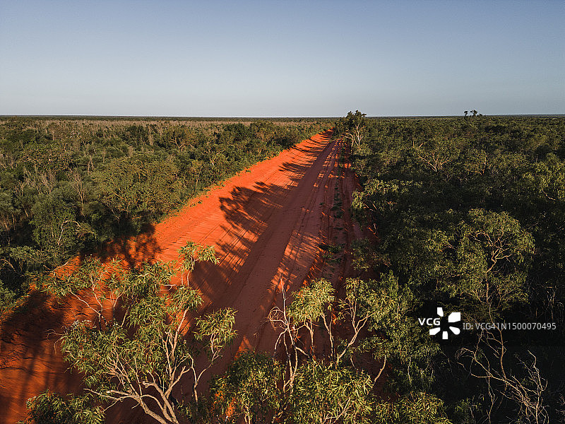 高角度拍摄的一条橙色土路穿过偏远的森林，澳大利亚西澳大利亚图片素材