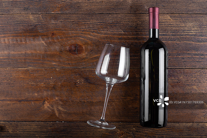 木制背景上的玻璃杯和一瓶红酒。俯视图图片素材