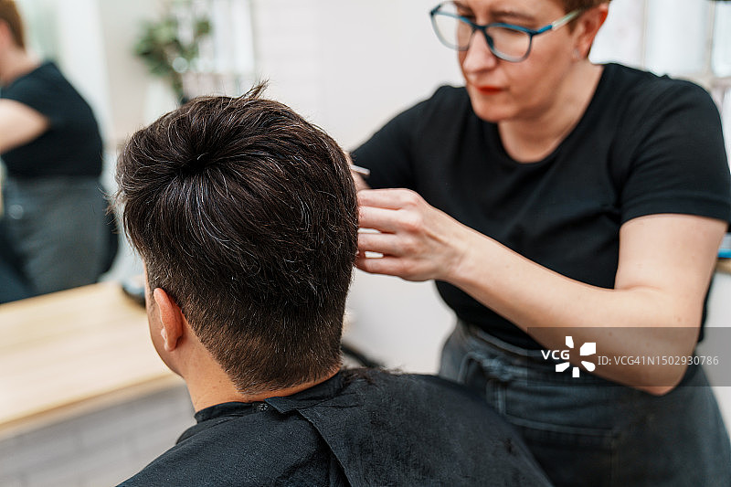 头发修复:在专业美发诊所，熟练的理发师修复脱发患者的假发图片素材