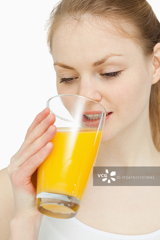 女人一边喝着橙汁一边看着它图片素材
