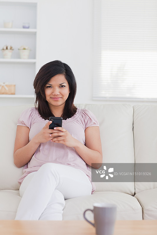 一个女人坐在沙发上，手里拿着电话图片素材