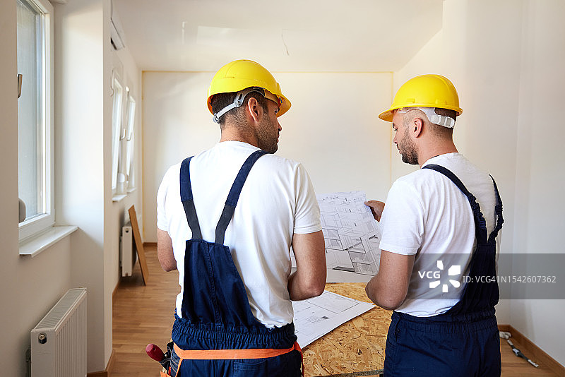 房屋装修过程中工人检查房屋工程的后视图。图片素材