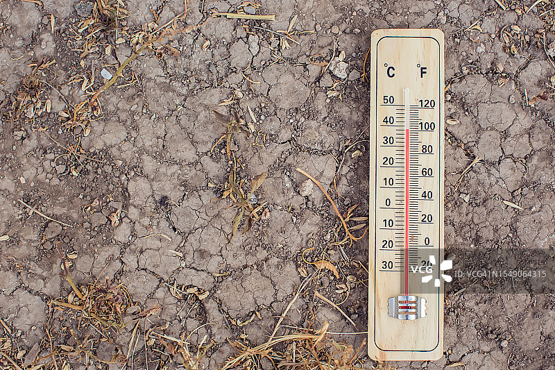 炎热的天气。热浪中，手持温度计站在城市前。高温概念图片素材