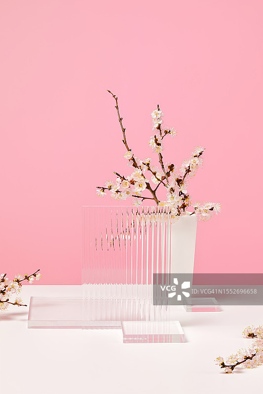 抽象的最小空3d舞台，精致的樱花枝在一个小花瓶和空的玻璃棱镜讲台在白色的桌子和柔和的粉红色背景与复制空间。图片素材