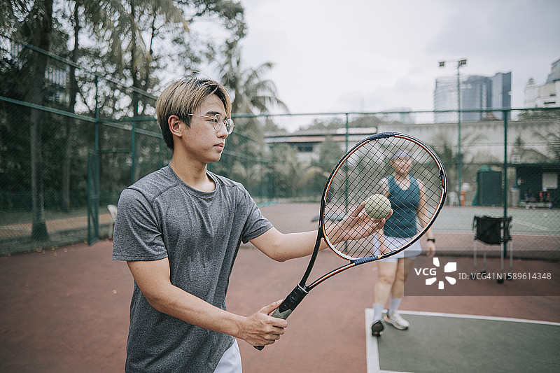 一个十几岁的亚裔中国男孩在网球场练习网球图片素材
