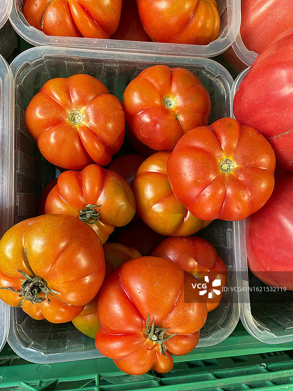 新鲜农产品超市货架单元的全画幅图像，绿色的塑料板条箱含有牛肉西红柿，高架视图图片素材